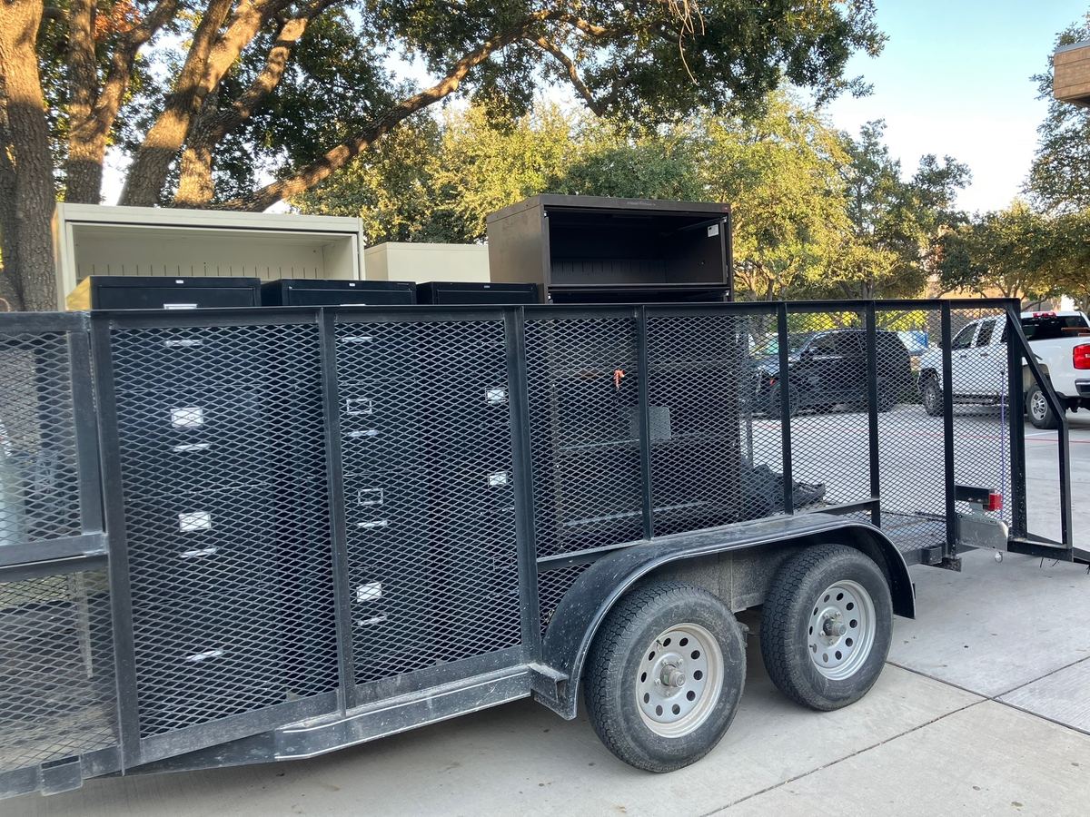 Metal file cabinets and office cabinets loaded on a mesh-sided hauling trailer