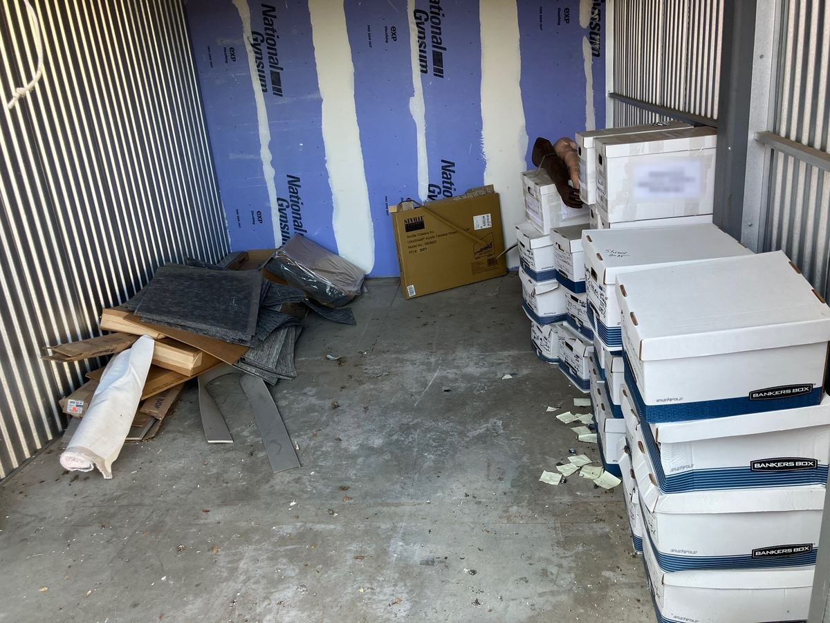 Storage unit with stacked file boxes, carpet tiles and cardboard before cleanout