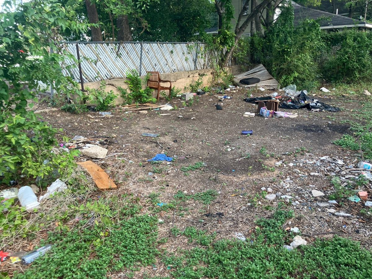 Vacant lot covered in trash, broken concrete and debris